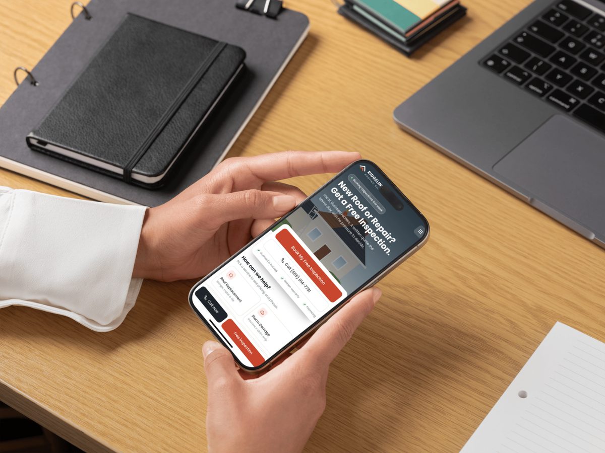 A person holding a phone showing a roofing company website with Book My Free Inspection and Call buttons.
